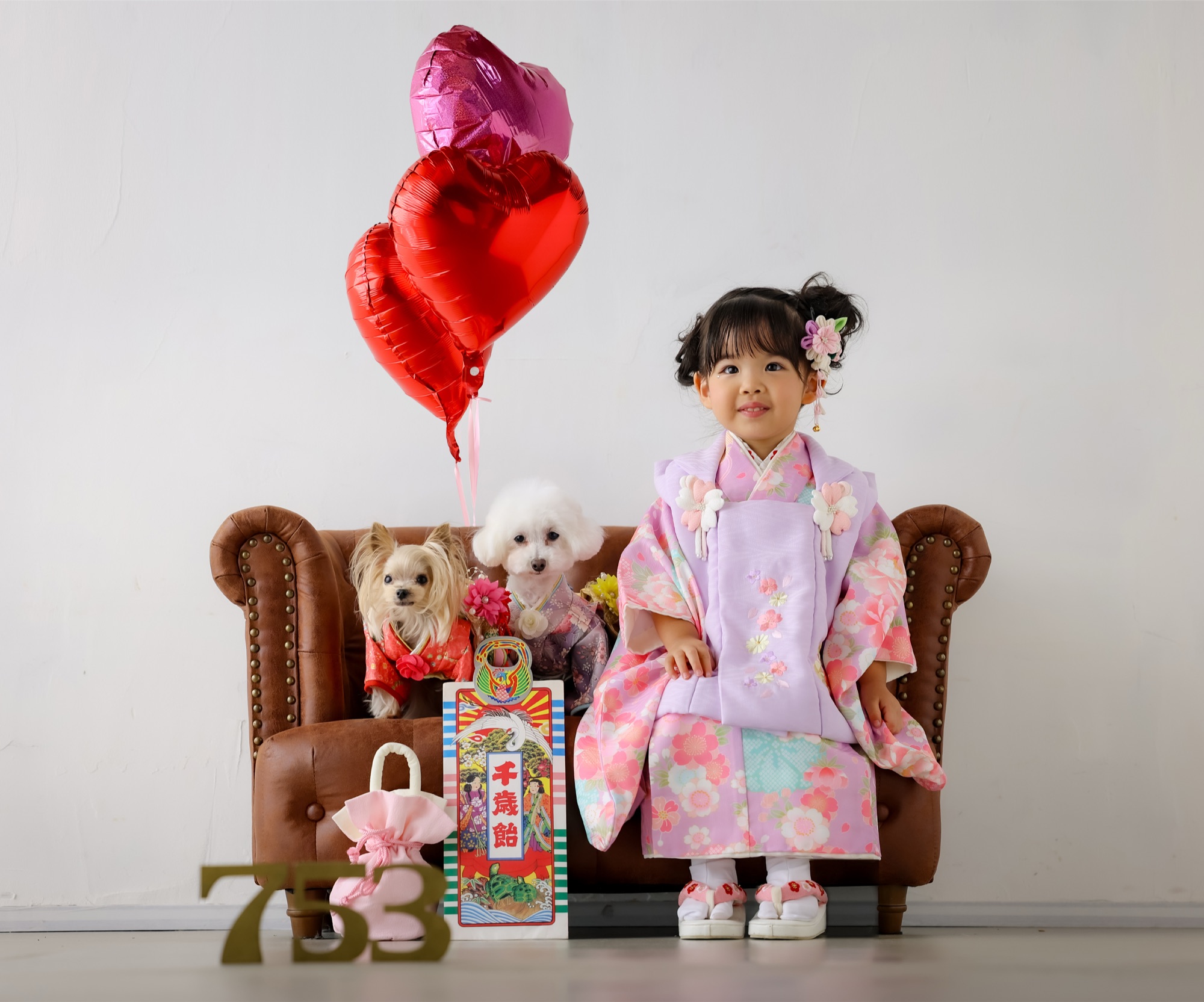 ハートの風船の前でソファに座る着物姿の女の子と2匹の愛犬｜ワンコと一緒に七五三